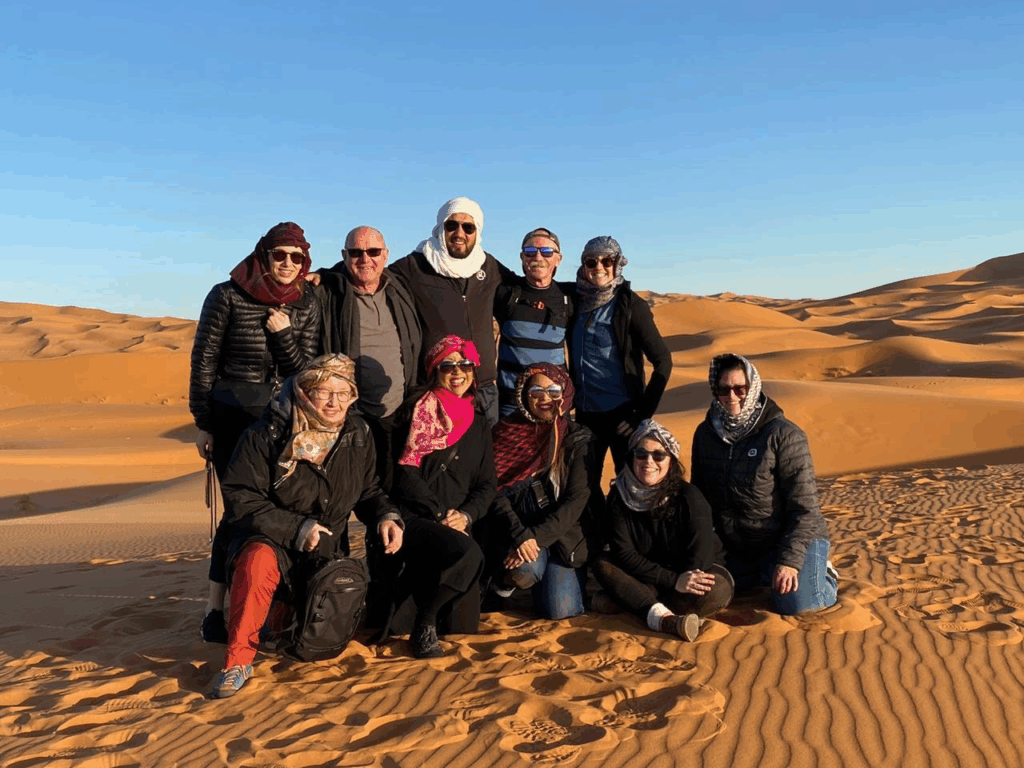 Friends joyfully experiencing the vastness of the Moroccan Sahara Desert.