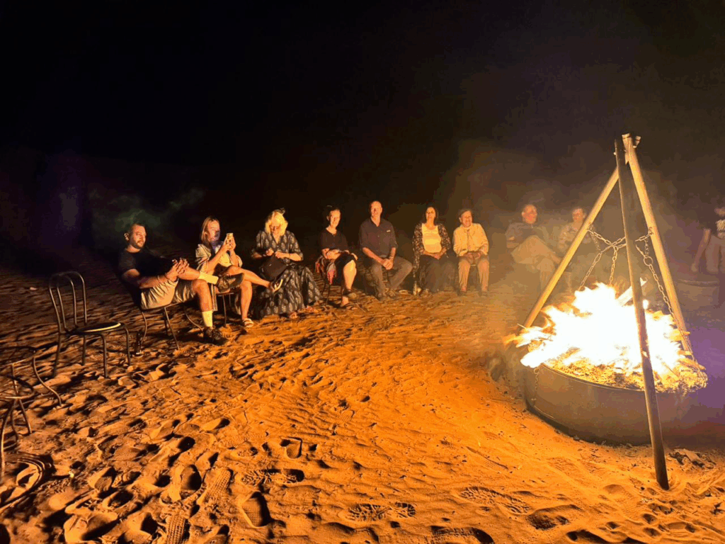 A group camping in the Sahara Desert at night.