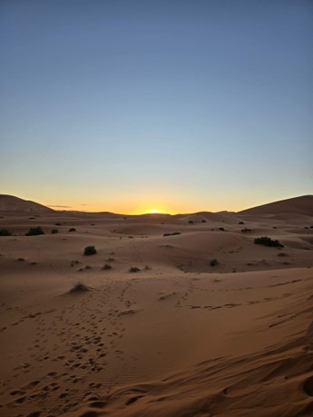 sunset at the desert with a clear sky and sandy mountains in distance