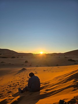a person sitting in the desert during sunset