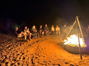 a group of people during a bonfire in the desert at night