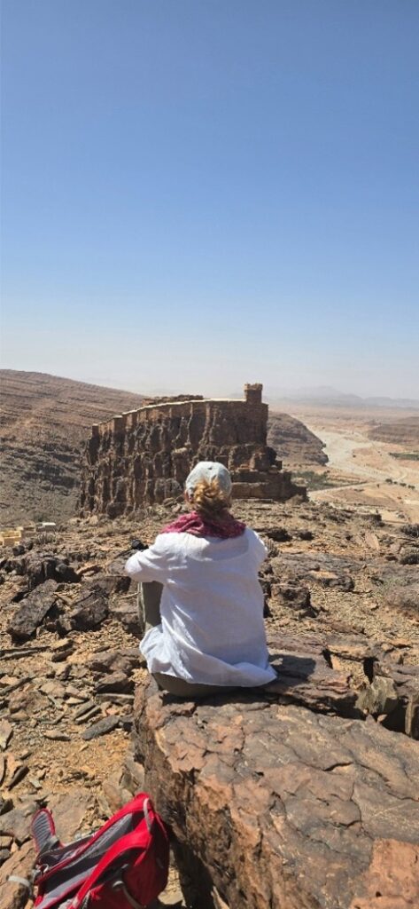 A woman sitting at the edge of a mountain to look at the view