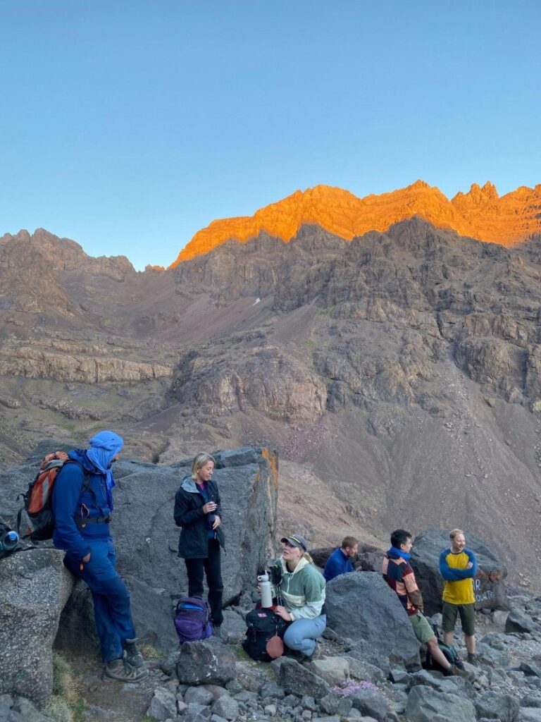 people taking in the view and talking to each other while resting on a mountain trek