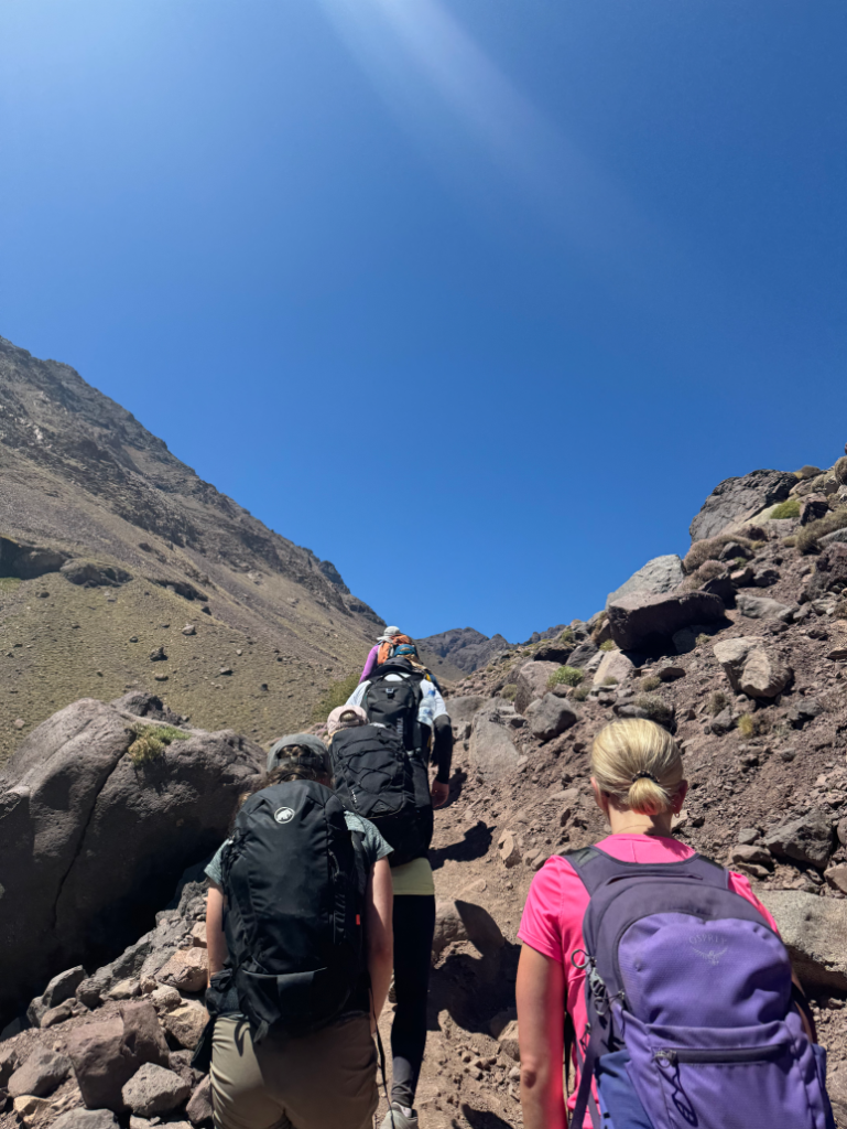 group of people climbing a mountain wearing backpacks