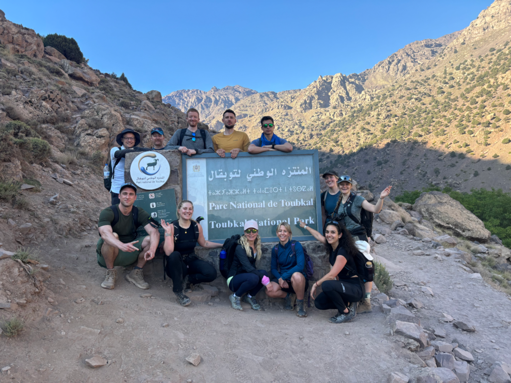 group of people posing for a picture with the Mt Toubkal sign