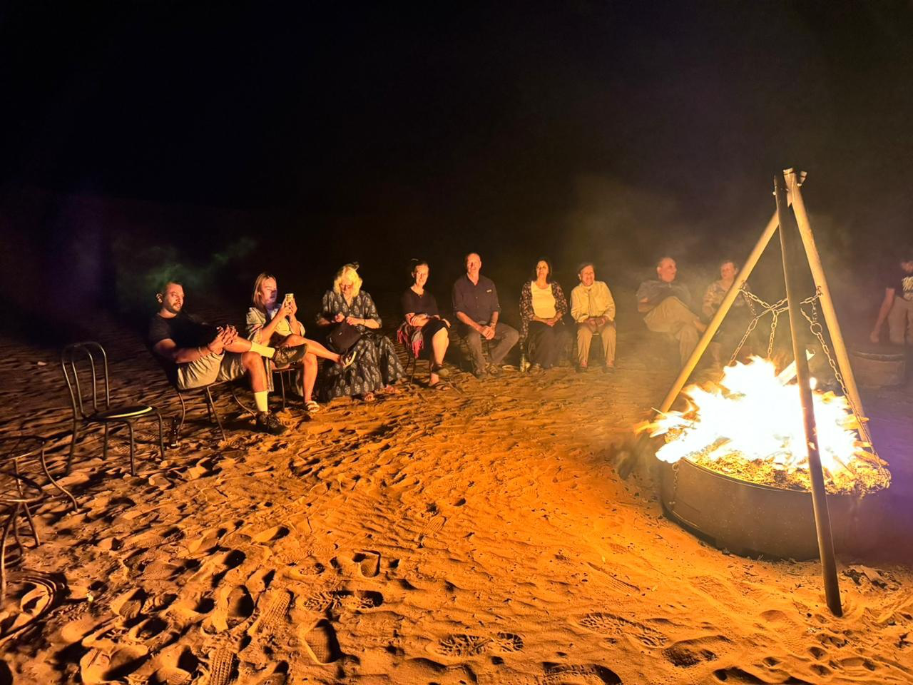 People sitting in the desert near a campfire