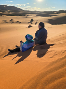 Two tourists sitting on sand in a desert