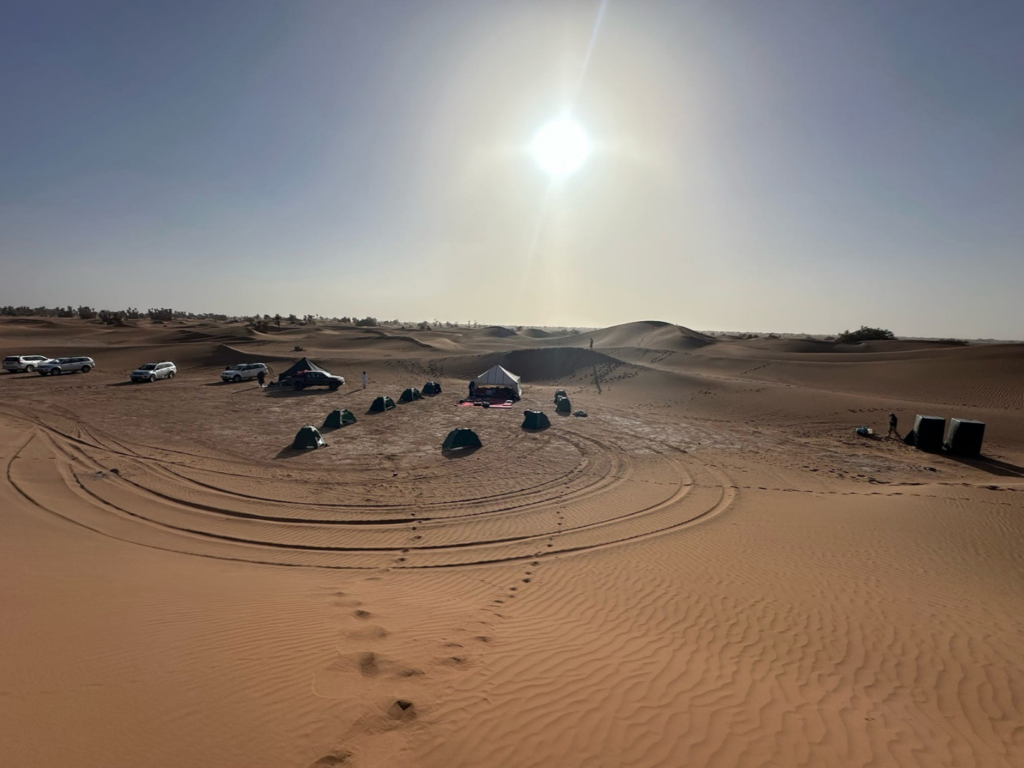 Cars and tracks dot the vast expanse of sand and dunes in the Sahara Desert, a sight to see during Moroccan multi-day excursion
